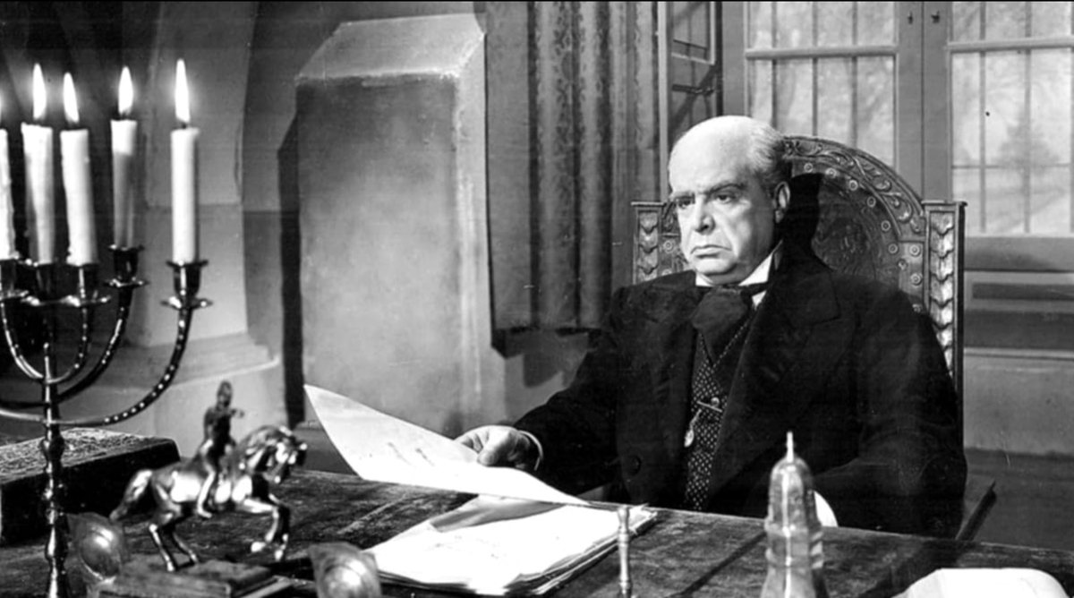 Enrique Muiño caracterizado como Sarmiento, en un escritorio a la luz de las velas